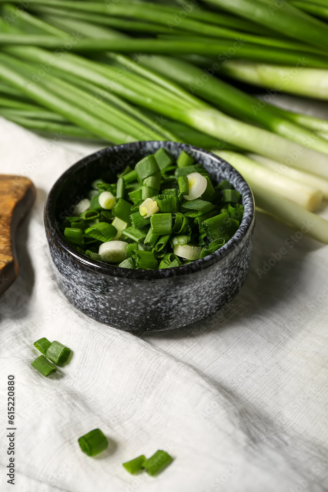 Bowl with fresh cut green onion on table