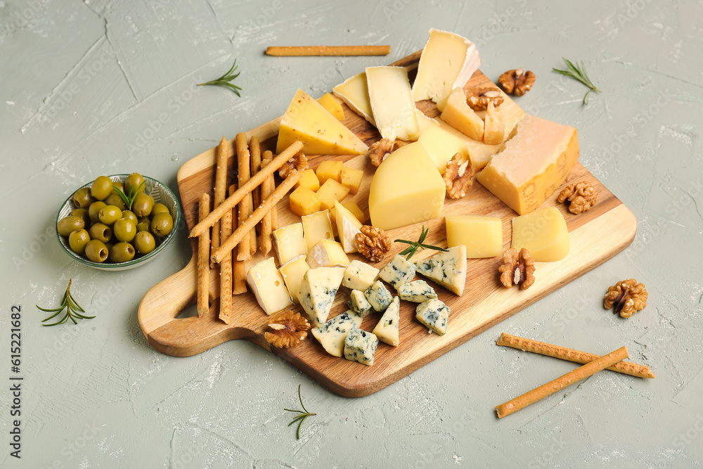 Wooden board with pieces of tasty cheese on light background