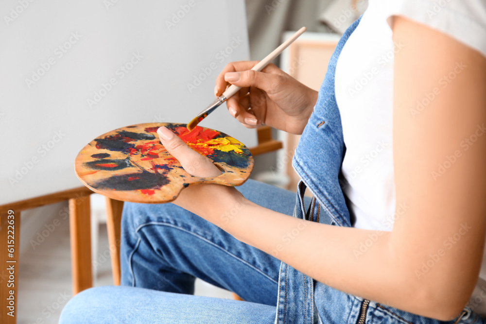 Female artist painting picture in  workshop, closeup