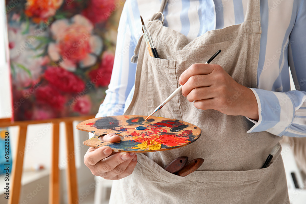 Mature female artist with palette and brush in  workshop, closeup