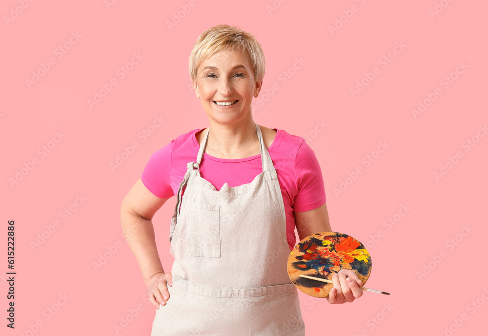 Mature female artist with tools on pink background