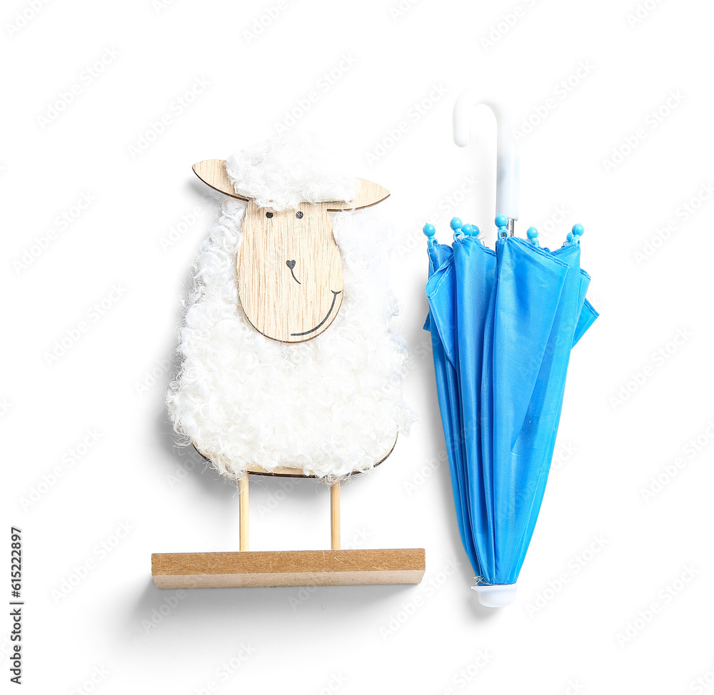 Creative composition with wooden toy sheep and mini umbrella on white background