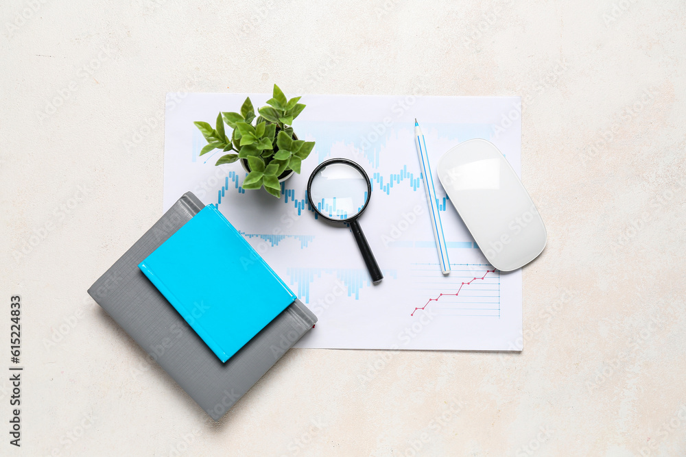 Magnifier with business charts on white table in office