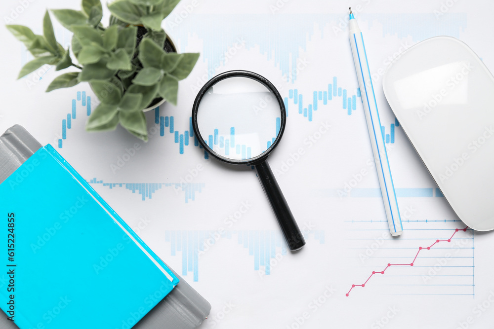 Magnifier with business charts on white table in office