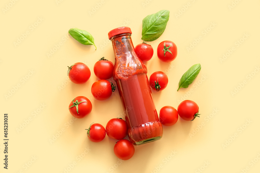 Glass bottle of ketchup and tomatoes on beige background