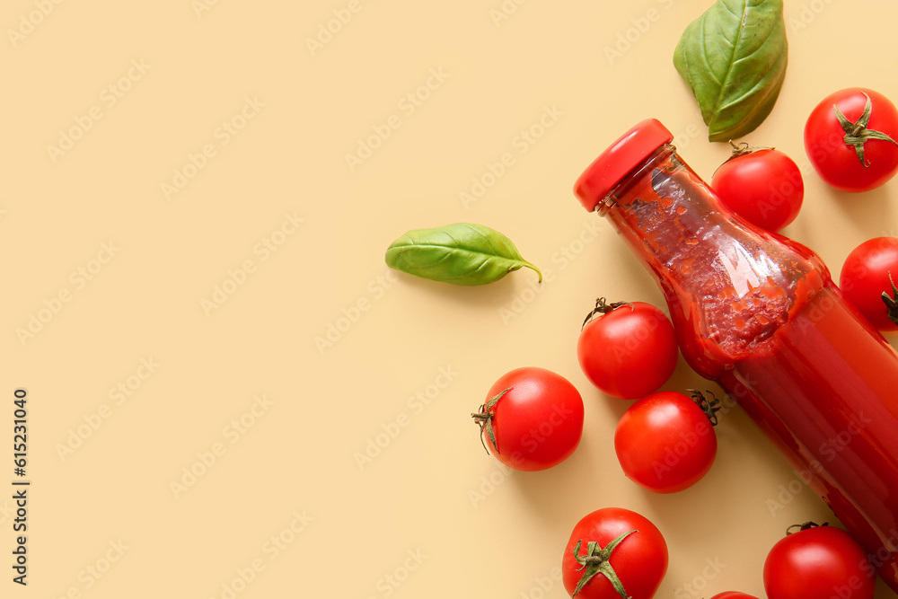 Glass bottle of ketchup and tomatoes on beige background