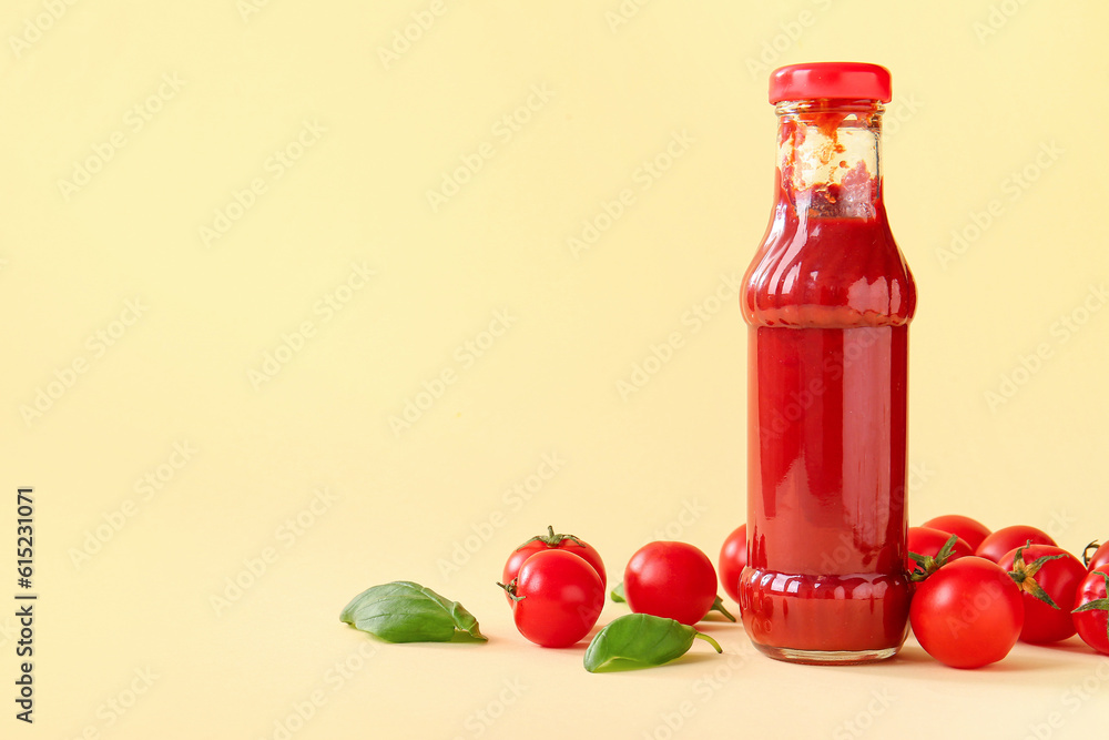 Glass bottle of ketchup and tomatoes on beige background