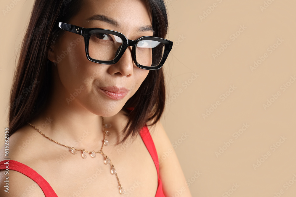 Beautiful Asian woman in stylish eyeglasses on beige background, closeup