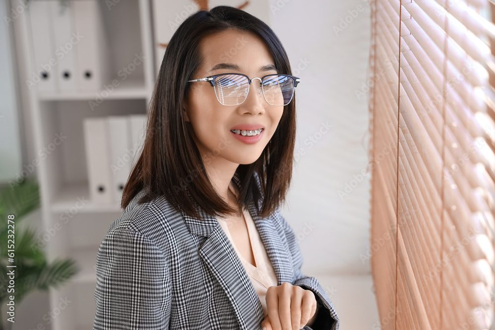 Beautiful Asian businesswoman in stylish eyeglasses in office