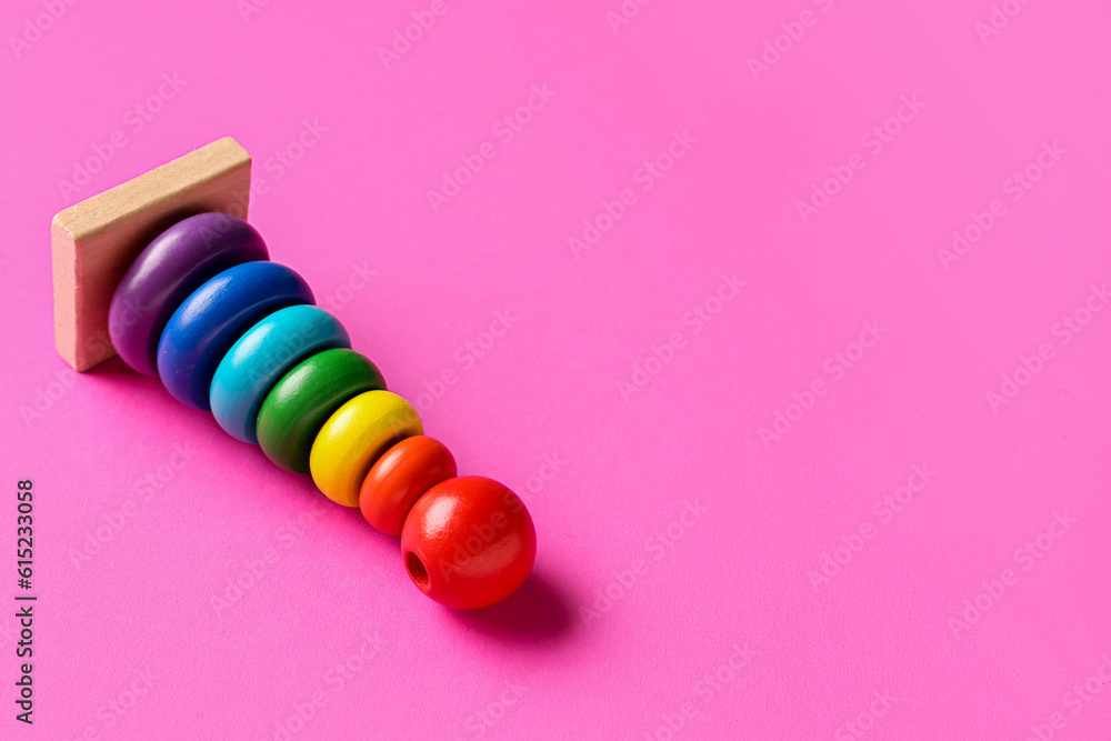 Wooden colorful toy pyramid on pink background. Childrens Day celebration