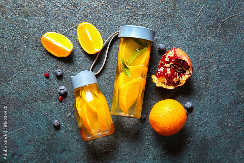 Sports bottles of infused water with orange slices on blue background