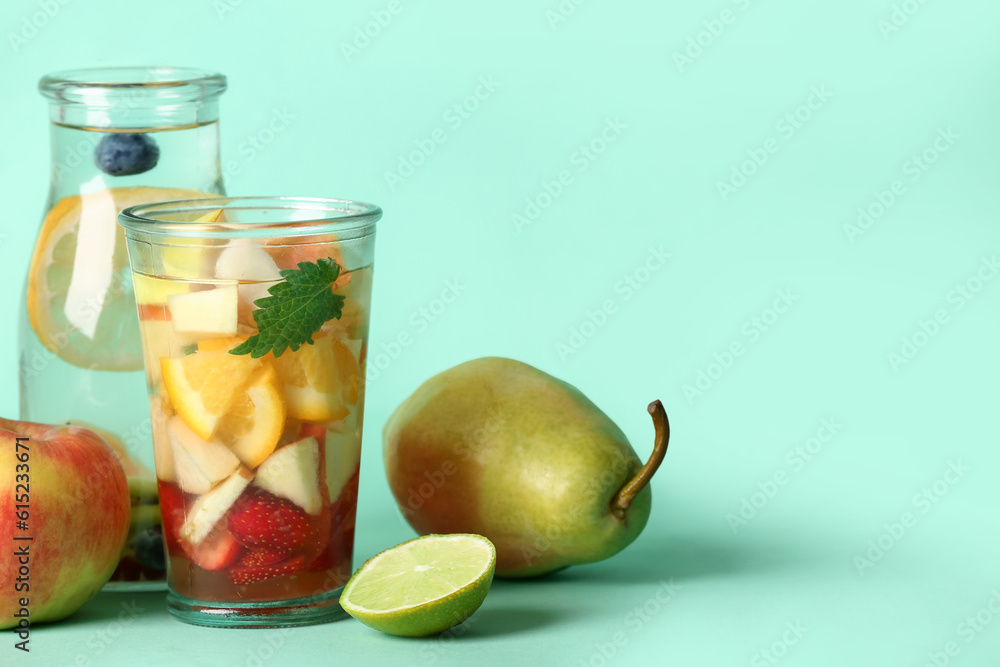 Glass and bottle of infused water with different sliced fruits on blue background