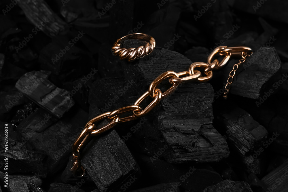 Beautiful chain bracelet and ring on black charcoal, closeup