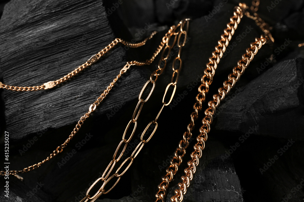 Beautiful chain necklaces on black charcoal, closeup