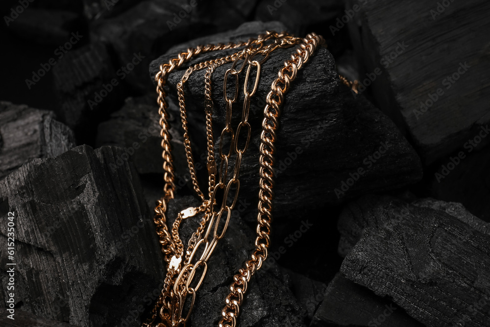 Beautiful chain necklaces on black charcoal, closeup