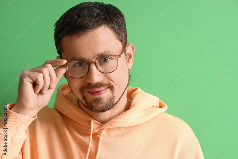 Handsome man in stylish eyeglasses on green background, closeup