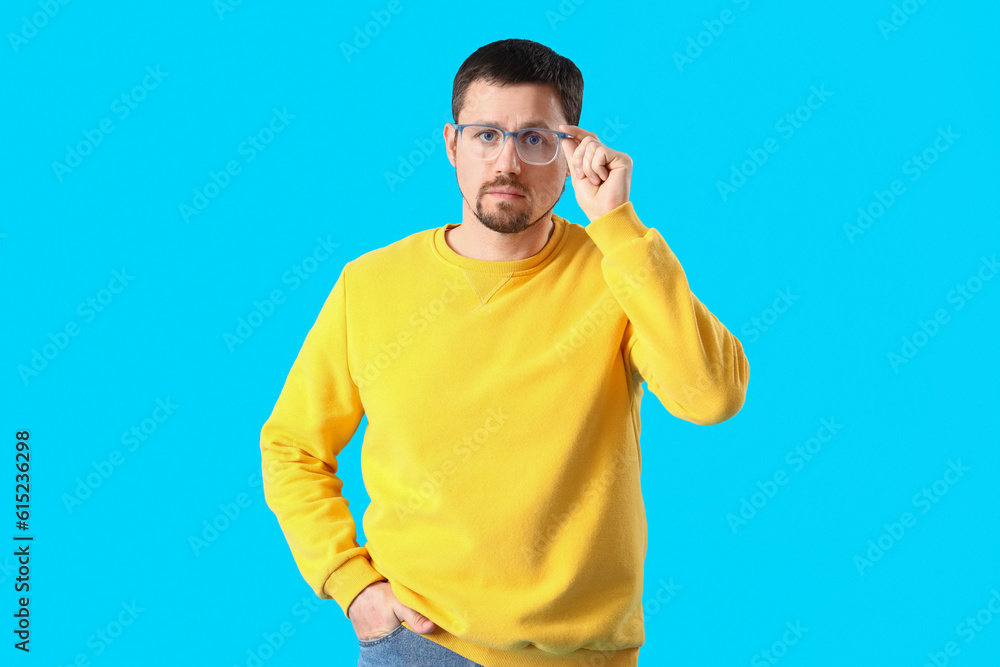 Handsome man in stylish eyeglasses on blue background