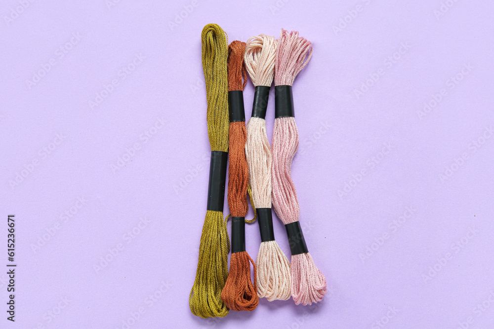 Different colorful mouline threads on lilac background