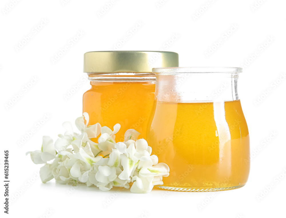 Jars of honey with flowers of acacia on white background