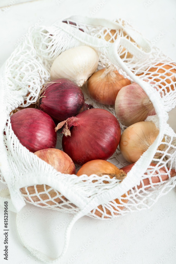 String bag with different kinds of onion on light background, closeup