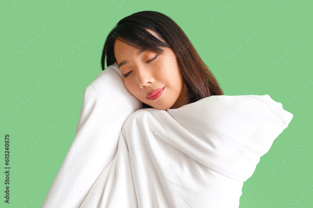 Beautiful Asian woman with blanket on green background, closeup