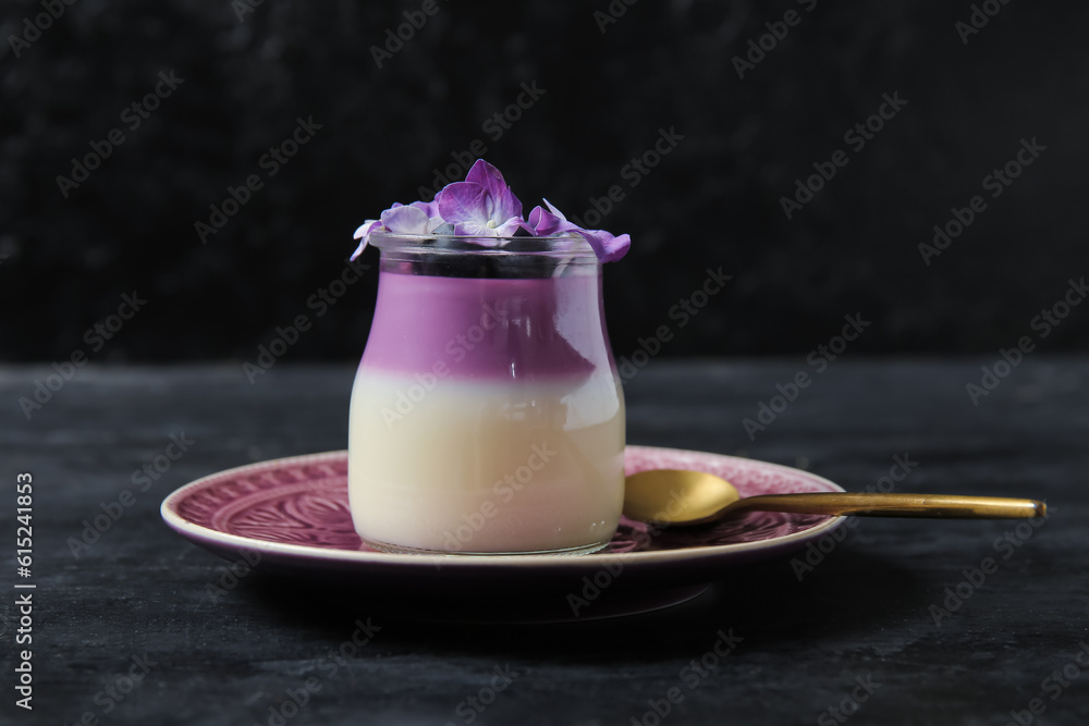 Glass of panna cotta with blueberry and beautiful hydrangea flowers on black table