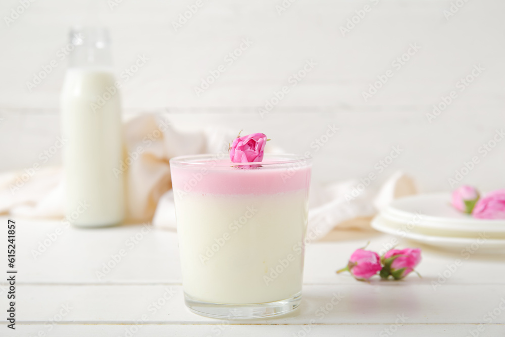 Glass panna cotta with beautiful pink rose flowers on white wooden table