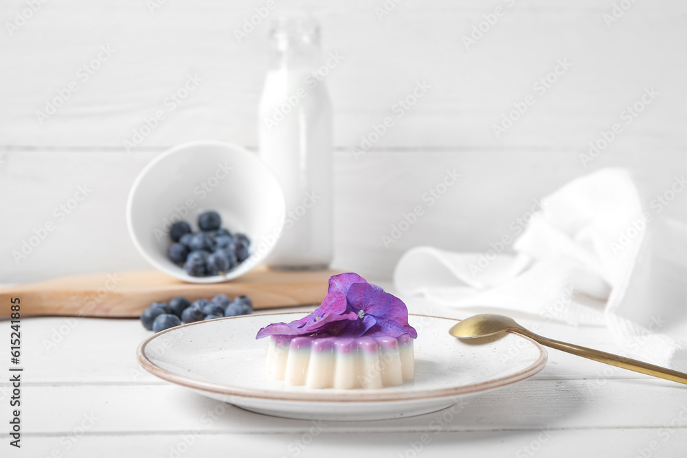 Plate of panna cotta with blueberry and beautiful hydrangea flowers on white wooden table