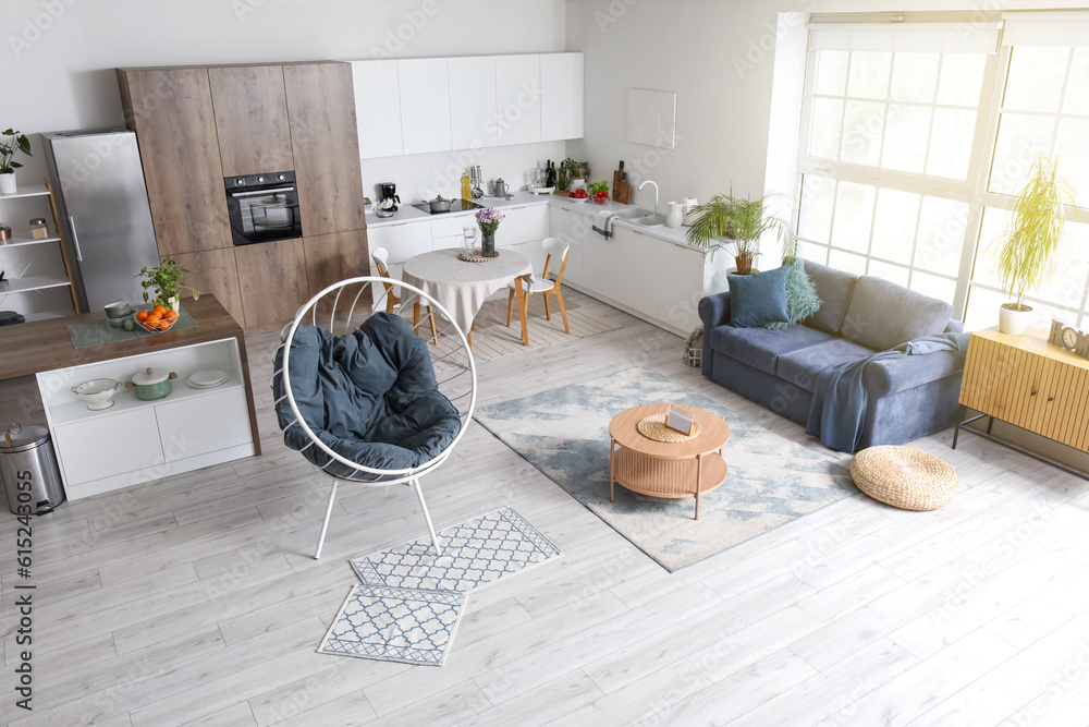 Interior of modern open plan kitchen with stylish sofa, armchair and coffee table