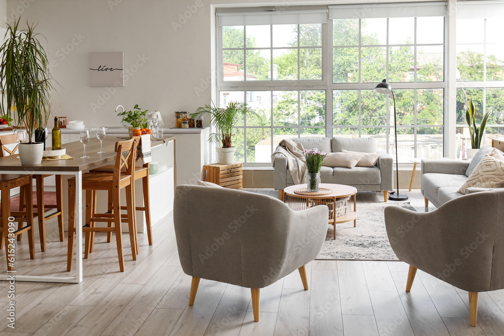 Interior of light open plan kitchen with coffee table, armchairs and sofa