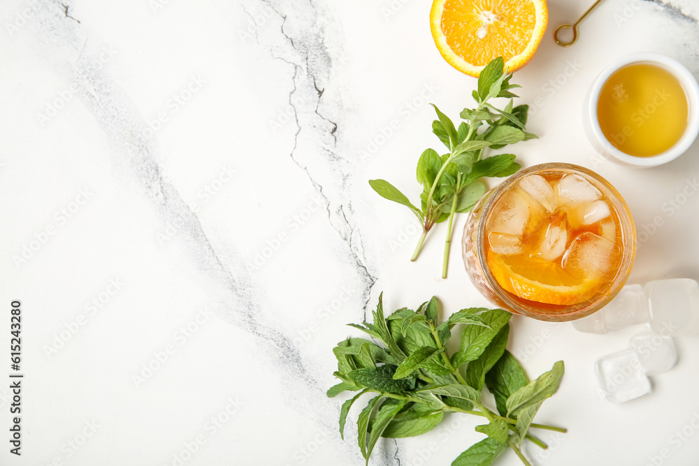 Glass of ice tea with orange and mint on white background