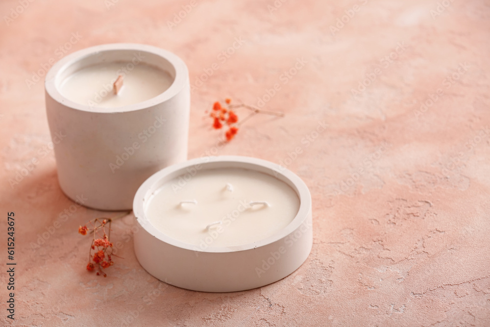 Holders with candles and flowers on pink background