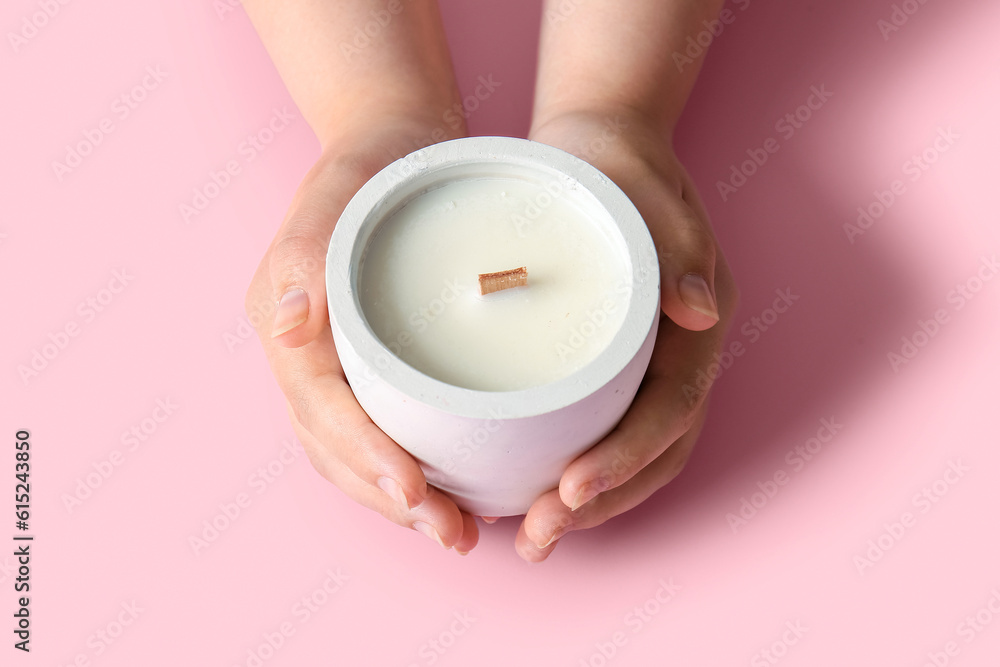 Female hands holding candle on pink background