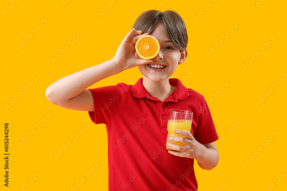 Little boy with orange and glass of juice on yellow background