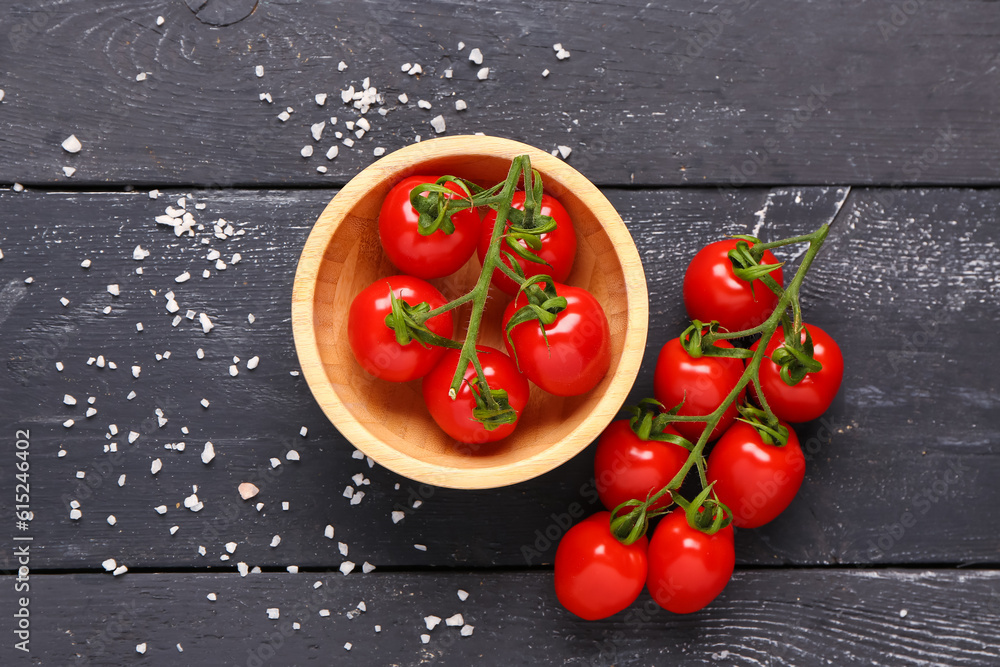 Bowl with fresh cherry tomatoes on black wooden background