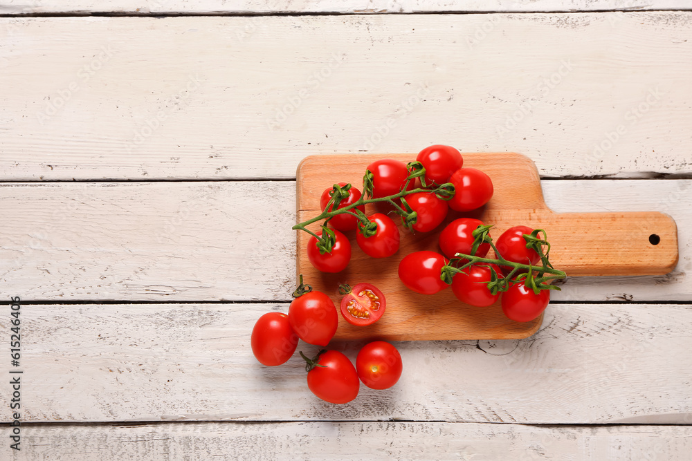 Board with fresh cherry tomatoes on white wooden background