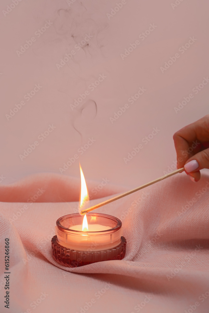 Hand of woman with match lighting candle