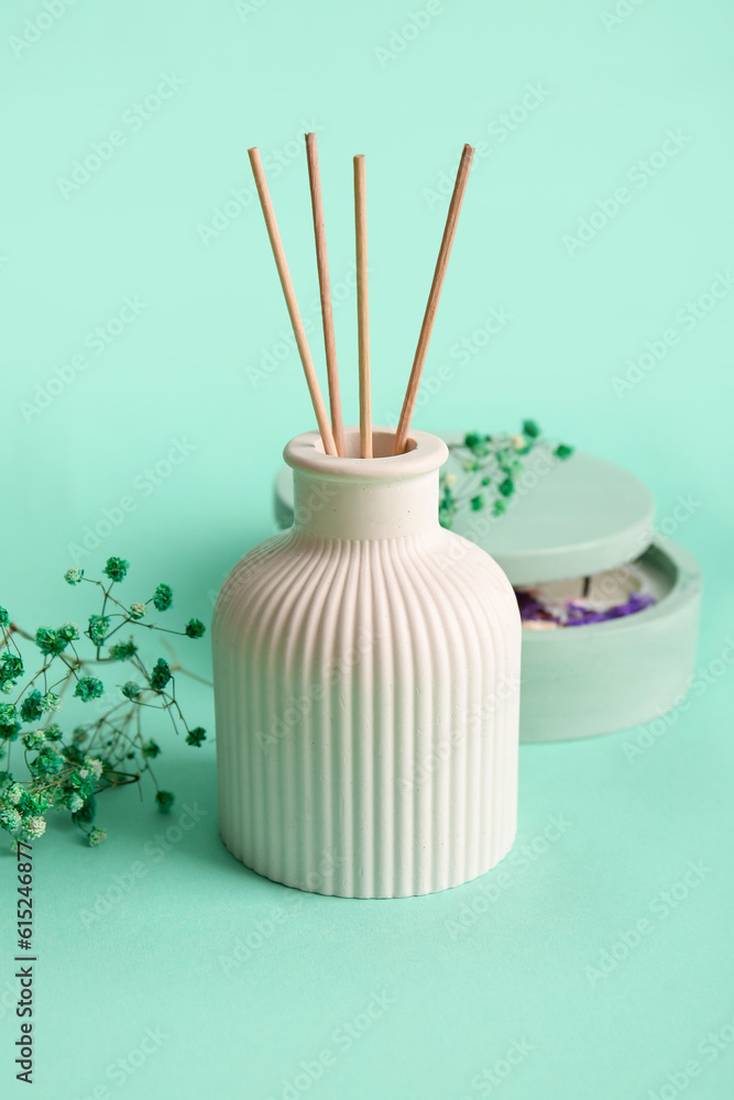 Floral reed diffuser and gypsophila flowers on turquoise background, closeup