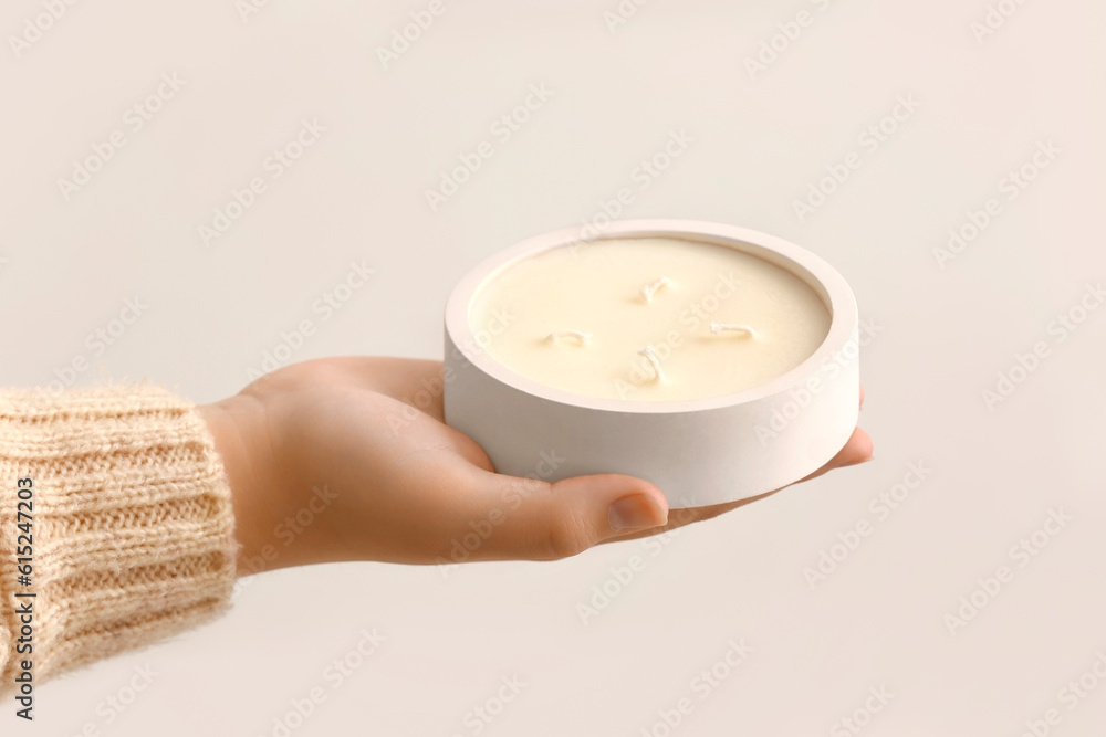 Woman holding candle on light background, closeup