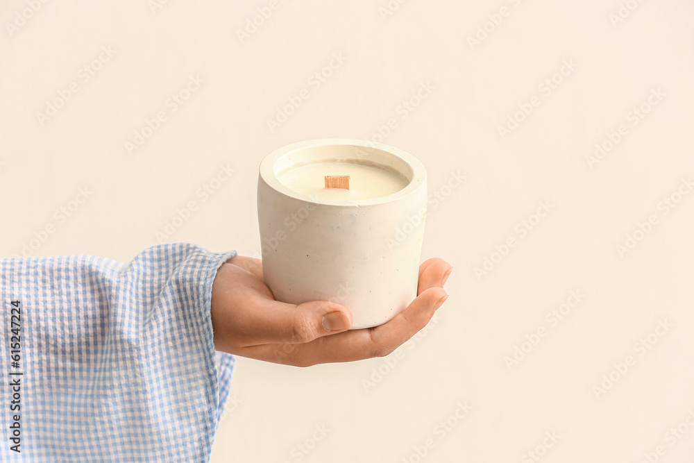 Woman holding candle on light background