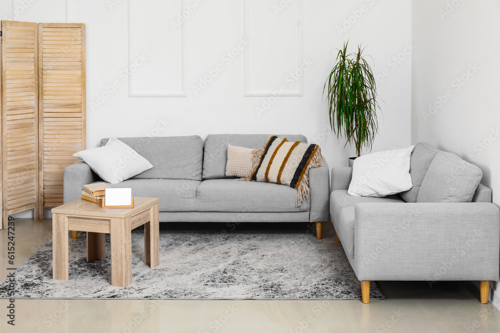 Interior of living room with cozy grey sofas and wooden coffee table