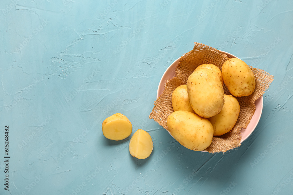 Bowl with raw baby potatoes on blue background