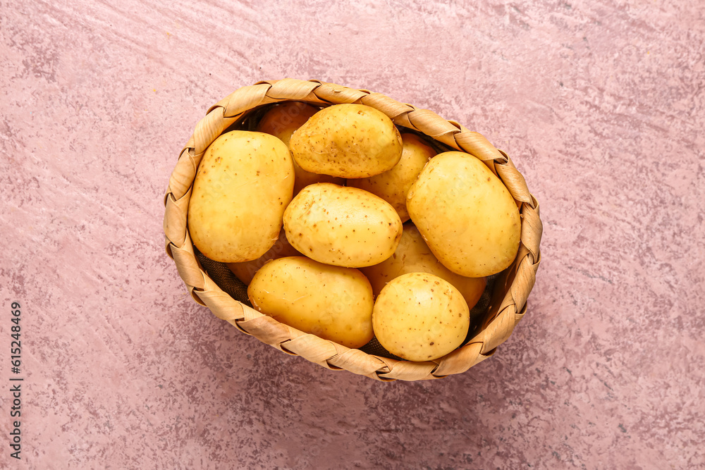 Wicker basket with raw baby potatoes on pink background