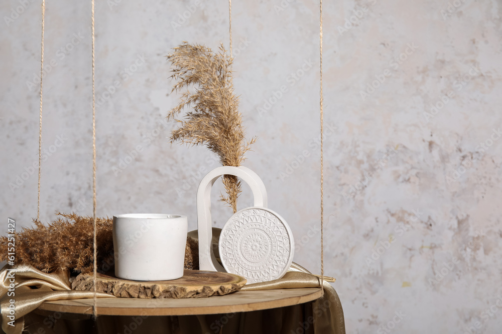 Holder with candle and pampas grass on hanging shelf near light wall in room