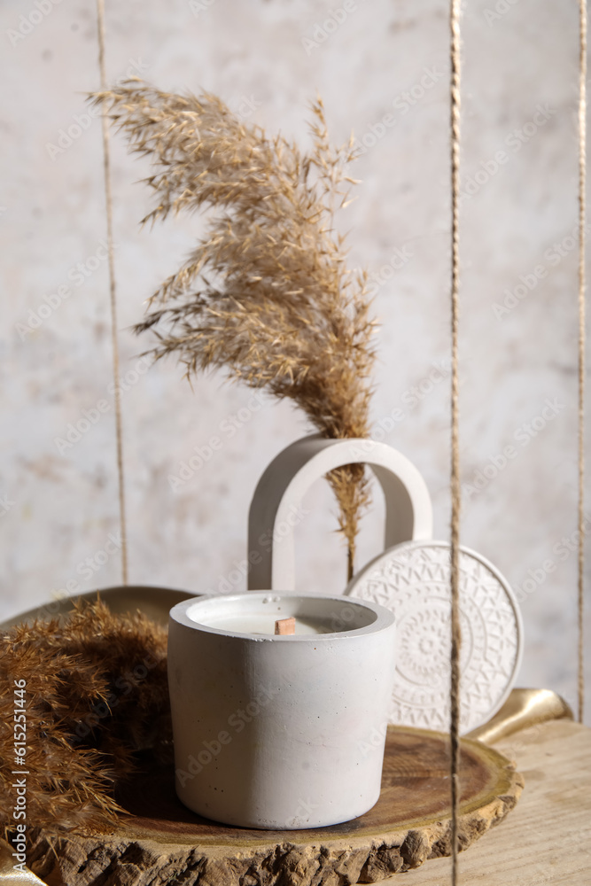 Holder with candle and pampas grass on hanging shelf near light wall in room, closeup