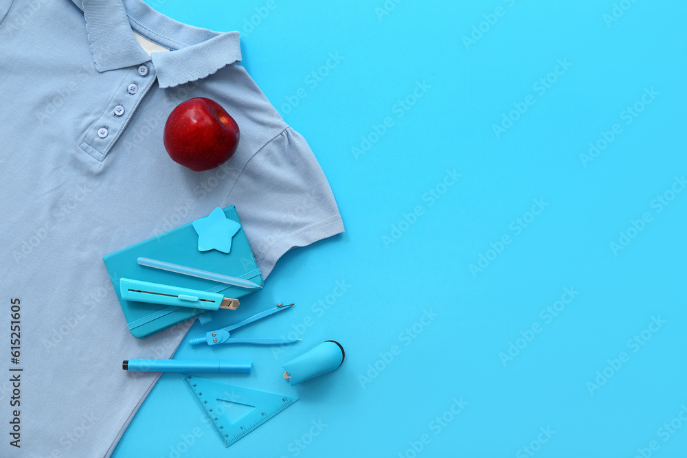 Stylish t-shirt with red apple and different stationery on blue background