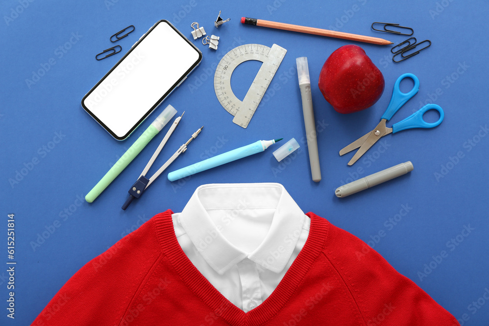 School uniform with fresh red apple, mobile phone and different stationery on blue background