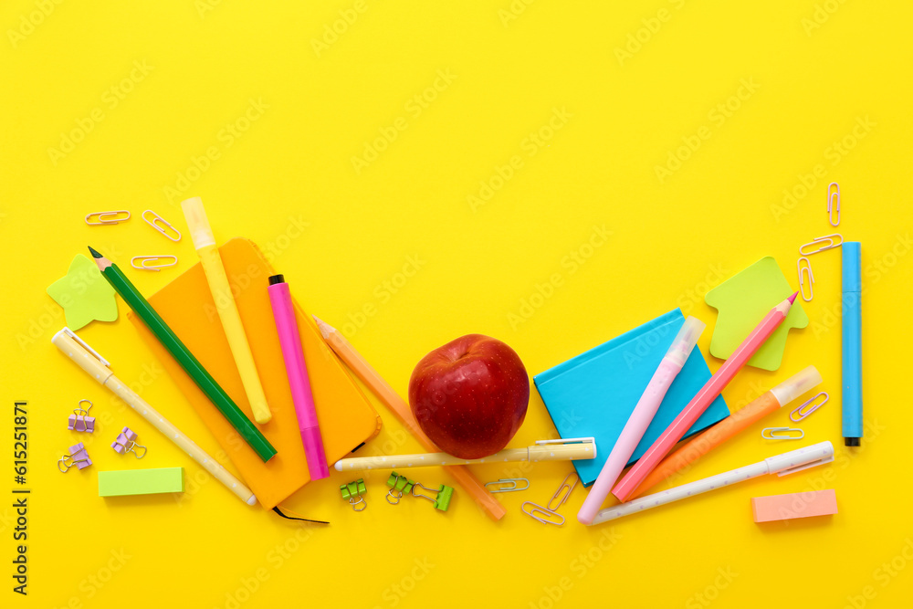 Fresh red apple with different stationery on yellow background