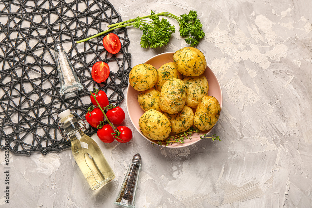 Bowl of boiled baby potatoes with dill and tomatoes on grey background