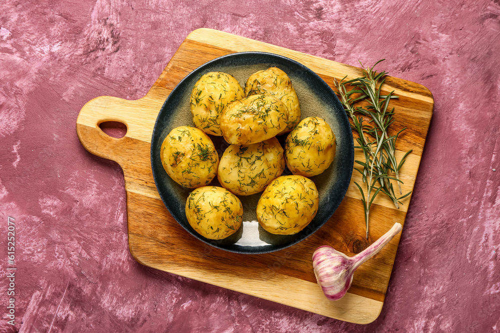 Plate of boiled baby potatoes with dill and garlic on purple background